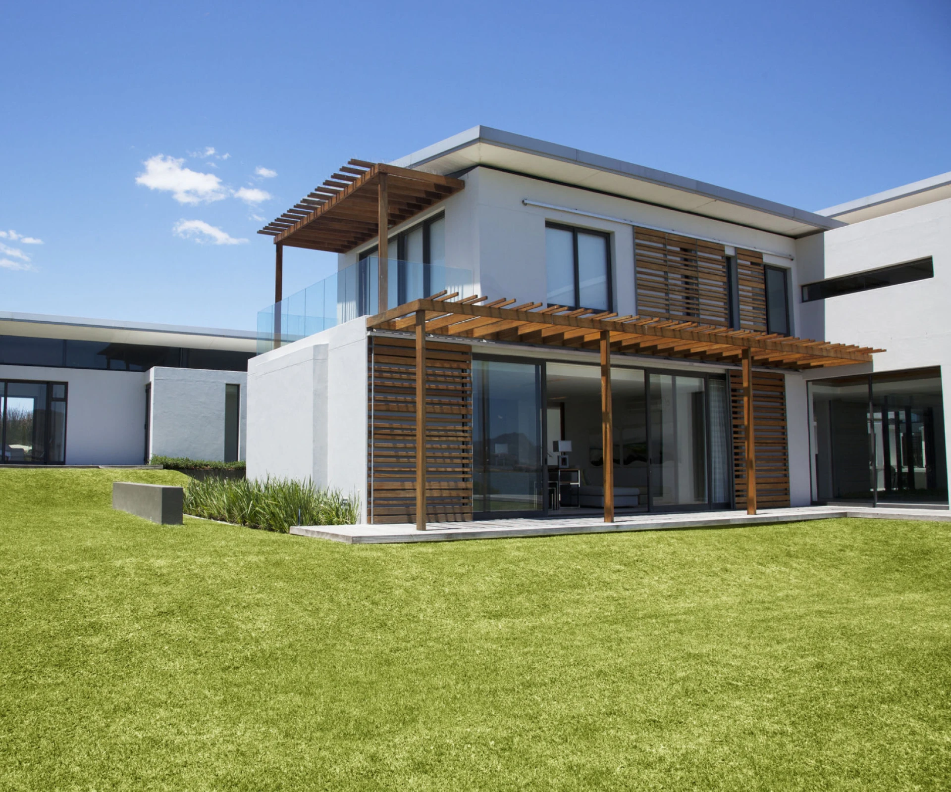 Modern house with wooden pergola and lawn.